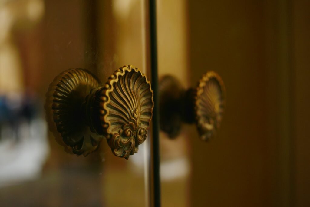 Close-up of ornate gold-toned door handles on glass, illustrating traditional decorative hardware