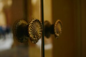 Close-up of ornate gold-toned door handles on glass, illustrating traditional decorative hardware